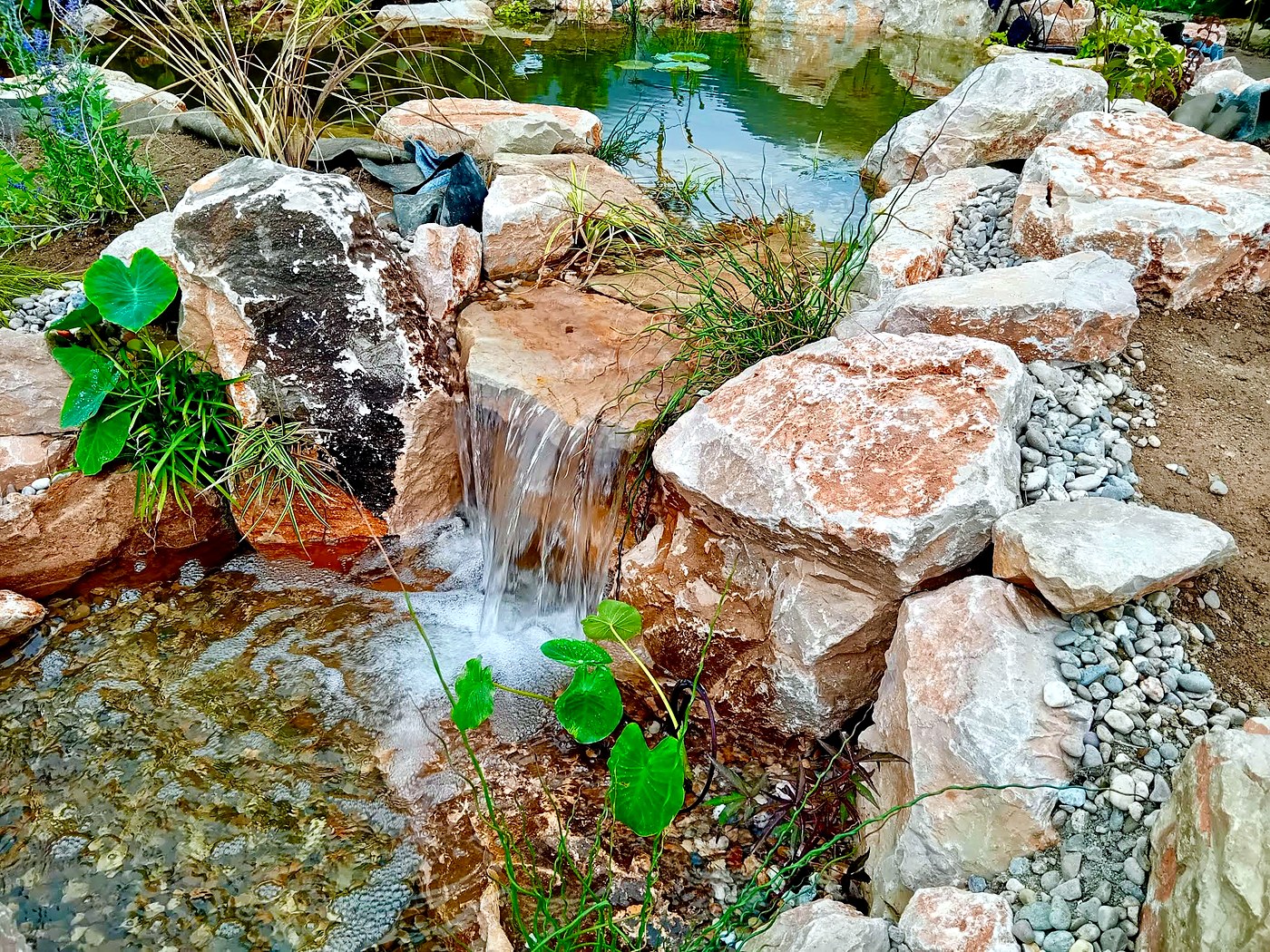 Hand-set stone waterfall feeding the limestone pool — Miranda do Corvo, Portugal